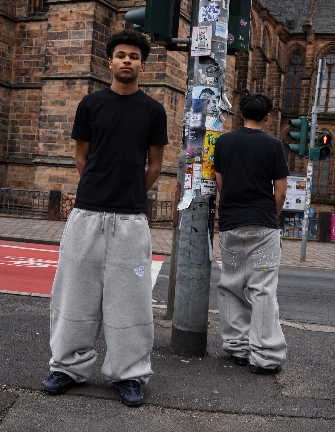 A man in a reda studio black tee and grey sweatpants on a wet autumn street